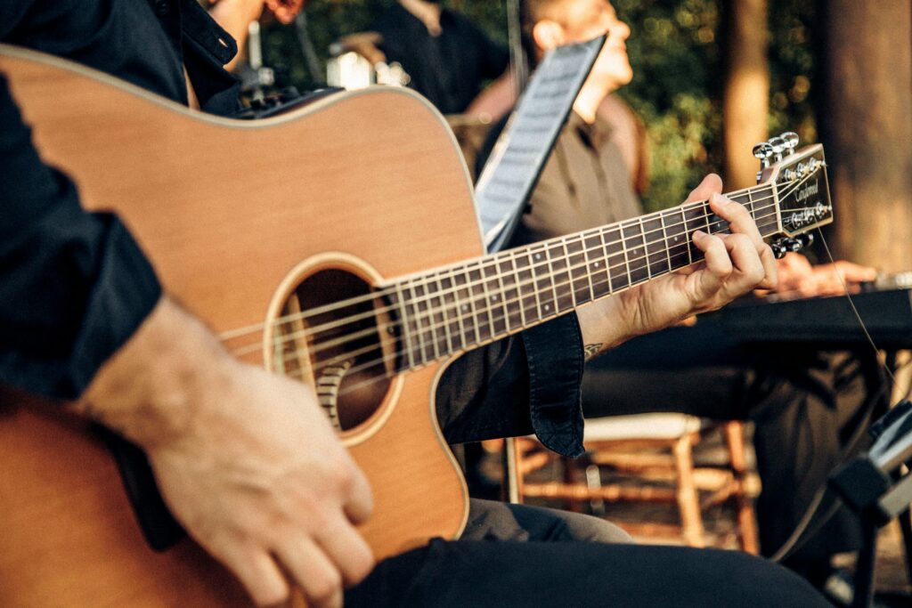pexels-photo-22679283-22679283 Close-up of a man playing an acoustic guitar at an outdoor concert, capturing the essence of live music.